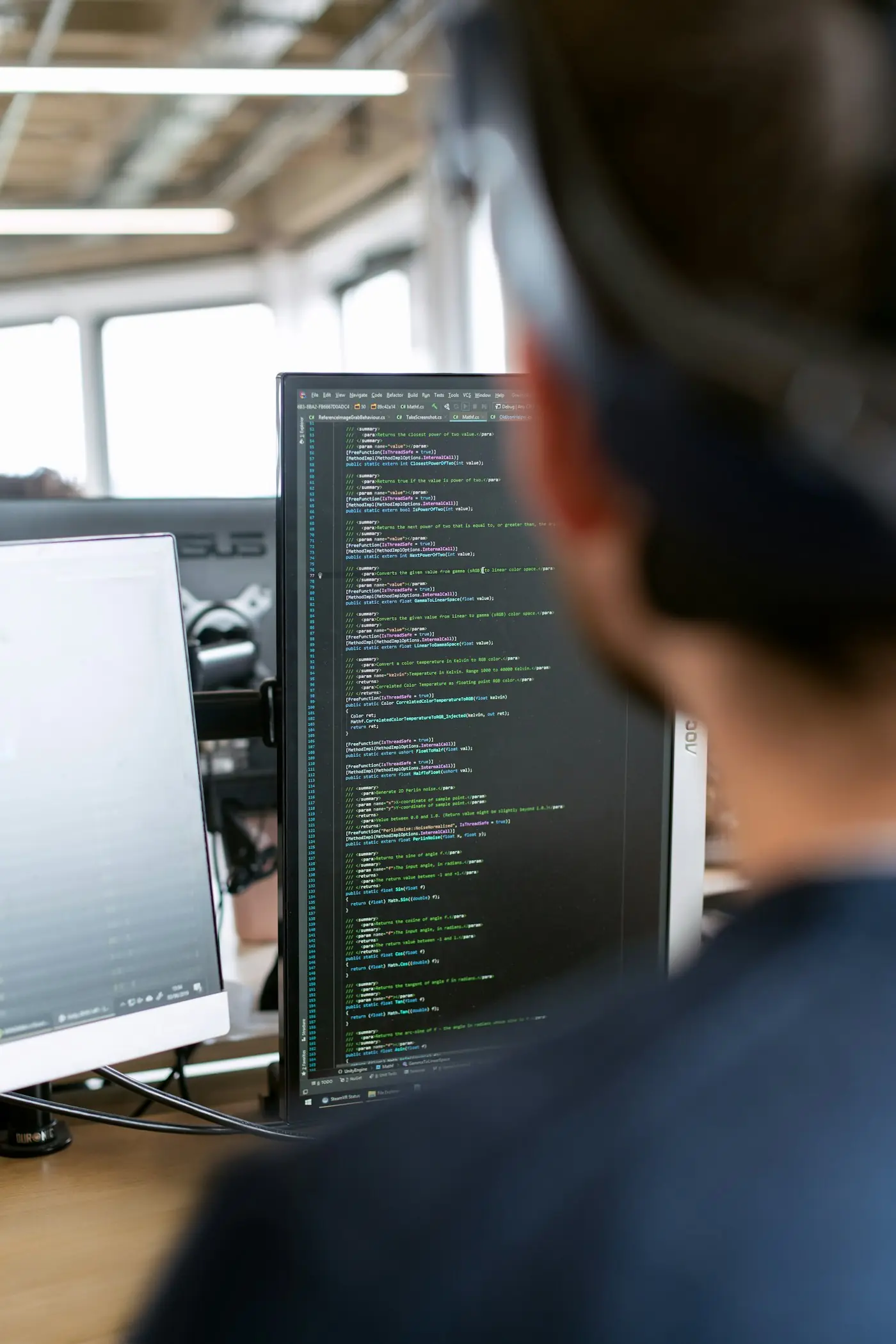 Person at a desk with monitors showing code